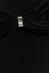 Vestido largo de punto negro con escote recto, hombros descubiertos, mangas largas y detalle de pieza metálica en el delantero.