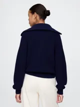 Sweater azul marino de tejido de punto grueso, con cuello polo con cierre de media cremallera y logo bordado en el pecho.