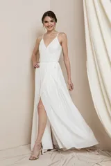 Vestido largo blanco con escote en V, breteles finos y falda plisada con abertura lateral. El corpiño está adornado con cuentas de cristal.