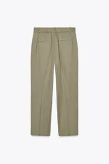 Pantalón color verde oliva de tiro medio con cintura con trabillas, bolsillos laterales, pinzas delanteras y raya planchada. Cierre frontal con cremallera, botón y ganchos metálicos.