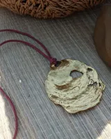 Collar con dije grande de bronce con forma de ostra y cordón de algodón ajustable color gris.