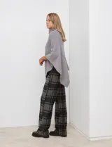 Poncho tejido color negro, con cuello polera y diseño de trenzas diagonales en el frente. Presenta un corte asimétrico en el ruedo.