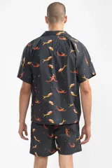 Short de baño azul marino con estampado de sirenas en tonos naranja y amarillo. Tiene cintura elástica con cordón ajustable, bolsillos laterales y trasero.