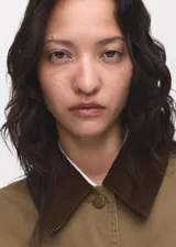 Chaqueta de algodón estilo tejano en color tostado, con diseño recto y manga larga con puños abotonados. Destaca por su cuello camisero de pana en contraste de color marrón oscuro, cierre frontal con botones y dos bolsillos de parche en el frente. Cuenta con forro interior.