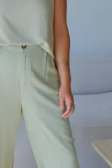 Pantalón de vestir ancho de tiro alto, color verde lima pálido, con textura de rayas verticales finas. Presenta pliegues frontales y cierre de botón visible.