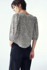 Blusa de tejido liviano con estampado de leopardo en blanco y negro. Modelo entallado con cuello redondo, cierre de botones y mangas globo tres cuartos con puños elásticos.