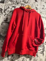 Canguro rojo con capucha y cordones ajustables, bolsillo tipo canguro y puños y cintura acanalados. Estampado con el logo de la marca en la manga.