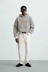 Sudadera con capucha a rayas horizontales blancas y negras, corte boxy fit, mangas largas y texto bordado en color rosa en el pecho.