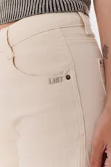 Pantalón de algodón color crema, de corte palazzo, tiro alto y ruedo desflecado. Incluye cinturón marrón con hebilla circular dorada.