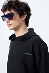 Canguro marrón con capucha, bolsillo frontal y puños ajustados. Estampa frontal con la palabra 'Dramatic' y gráfico en la espalda con tipografía bold y serpiente ilustrada.