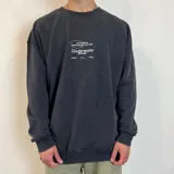 Buzo color crema de corte oversize con cuello redondo y puños acanalados. Presenta estampados en negro con motivos de palmeras, calamar, texto y logo de la marca.