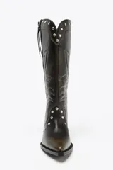 Bota de caña alta color marrón oscuro con bordados en contraste y tachas plateadas. Cierre con cremallera frontal y tacón bloque bajo.