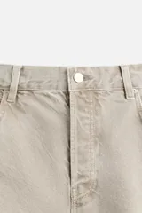 Pantalón de jean color beige, de corte amplio y tiro alto. Tiene cinco bolsillos, cierre frontal con botones y detalle de costuras laterales dobles.