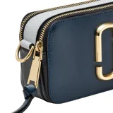 Bolso bandolera Marc Jacobs modelo The Snapshot, color verde oscuro con detalles dorados y correa ancha de tela con el logo de la marca en azul y negro.