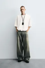 Camiseta blanca de algodón, corte holgado, cuello redondo, manga corta y bajo con elástico interior.