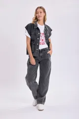 Chaleco de jean negro con cuello camisero, cierre frontal con botones, bolsillos de parche y sisas desflecadas.