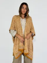 Ruana color crudo de tejido de punto calado con terminación en crochet.