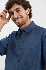 Camisa de manga corta azul con estampado de lunares blancos, cuello button-down y bolsillo en el pecho.