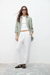 Camisa verde seco de lino, de corte holgado, con cuello clásico, cierre frontal con botones, manga larga y bolsillo de parche en el pecho.