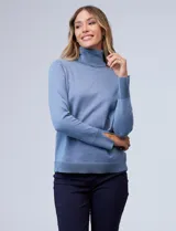 Polera de punto fino color celeste, con cuello alto, manga larga y detalle de tajo en los puños.