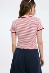 Remera corta de algodón a rayas horizontales blancas y rojas, con cuello y mangas con ribete al tono.