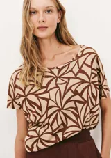 Blusa de viscosa color beige con estampado de hojas marrones, corte holgado y mangas cortas.