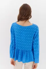 Camisa celeste de algodón con textura arrugada y bordados a tono, escote amplio, mangas largas y botones frontales.