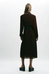 Vestido midi marrón chocolate plisado, con cuello solapa, manga larga y cinturón. Presenta cierre frontal con botones y vivos blancos a contraste en cuello, mangas y botonera. Incluye forro interior.