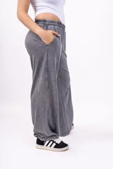 Pantalón deportivo gris con efecto lavado, corte ancho, cintura elástica y logo bordado en negro.