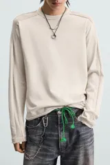 Camiseta color beige de corte relaxed fit, con cuello redondo y mangas largas combinadas con tejido de red.