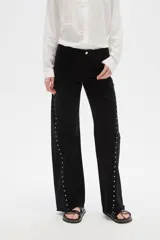 Pantalón jean negro de tiro alto, corte flare y detalle de tachas plateadas en los laterales.