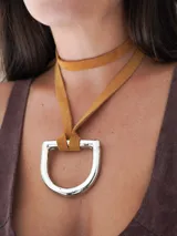 Collar con tira de cuero color suela y dije metálico dorado en forma de estribo.
