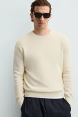 Jersey color crema de punto perlado, con cuello redondo, manga larga y corte regular fit.