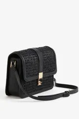 Bandolera negra con textura tejida, correa fina ajustable y solapa con cierre metálico dorado.