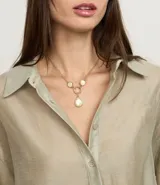 Collar corto dorado con colgantes de resina color crema y aro dorado. Cierre con tornillo.