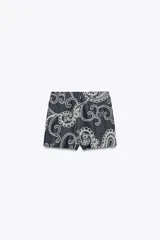Falda pantalón corta de tiro alto color azul denim con bordados florales blancos.