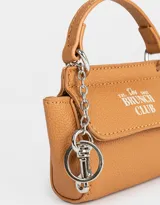 Monedero de cuerina color crudo con estampado de motivos japoneses y la palabra "Tokyo". Tiene forma de bolso con manija superior, solapa con broche a presión y mosquetón lateral.