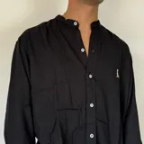 Camisa blanca de lino con cuello mao, manga larga y corte regular. Presenta un pequeño bordado en el pecho.