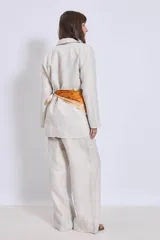 Blazer color crema de lino con corte clásico, solapas de muesca y cierre cruzado con un botón. Incluye un pañuelo de seda estampado atado a la cintura.