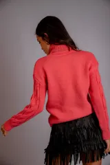 Sweater verde esmeralda de punto trenzado, con cuello alto y mangas largas.