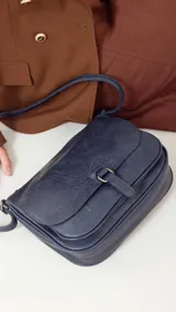 Bandolera color tostado con tapa y broche, bolsillo principal y bolsillos internos organizadores, cierre trasero y correa larga regulable.