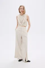 Top cropped color crudo, calado, al cuerpo y cuello a la base, sin mangas y con volados en los hombros.