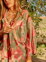 Vestido camisero de lino con estampado de palmeras en tonos rosados y verdes.