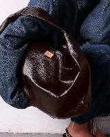 Bolso marrón oscuro de cuero sintético con forma ovalada y asa corta.
