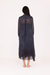 Vestido camisero largo midi de calce recto, confeccionado en tejido liviano y semitransparente de color azul oscuro. Presenta cierre frontal con botones, cuello mao, mangas largas con puño y terminaciones irregulares en el bajo.