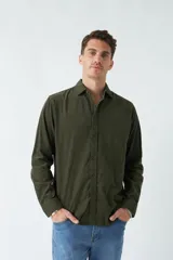 Camisa de pana color verde militar, de corte regular, con cuello clásico y cierre frontal con botones.