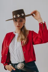 Campera bomber color beige de cuero, con cuello redondo, cierre frontal con botones a presión, mangas largas con puños elásticos y detalles de tachas metálicas en hombros y espalda.