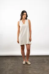 Vestido corto color crema, de lino, sin mangas y con escote en V.