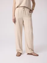 Pantalón color beige de corte holgado con cintura elastizada y cordón ajustable.