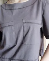 Remera negra con cuello redondo y mangas cortas, con detalle de pespuntes blancos en cuello, mangas, bolsillos frontales y ruedo.